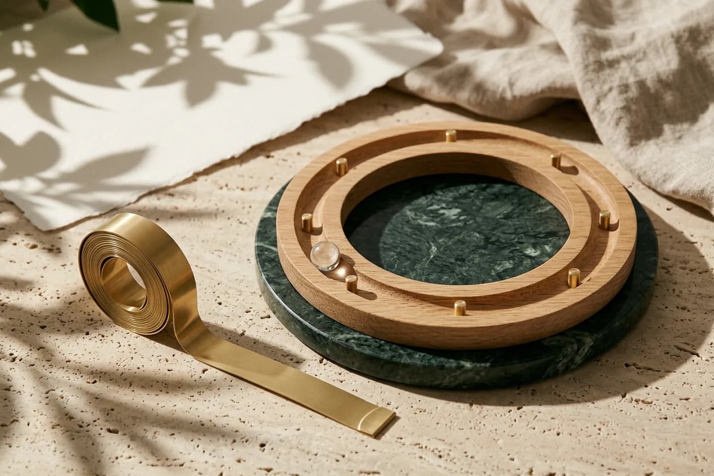 A glass bead resting against a brass stop pin on a circular oak track on a green marble base, with an unrolled brass measuring tape beside it.