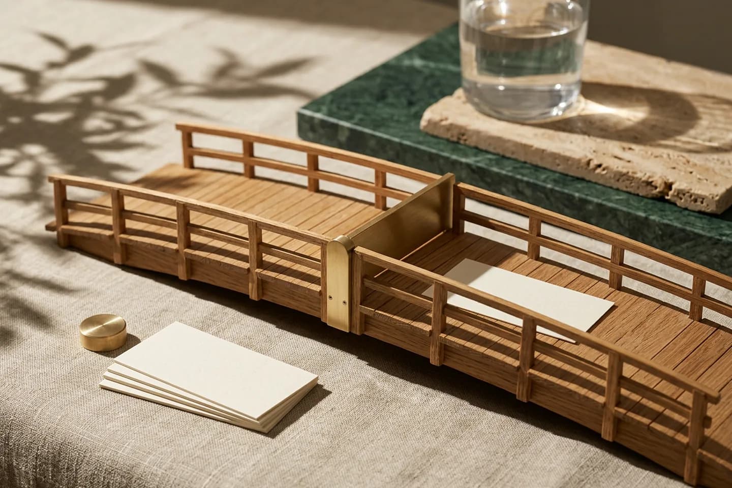 A miniature oak bridge with a brass gate across its middle, blank paper slips waiting on one side and a single slip placed beyond the gate.