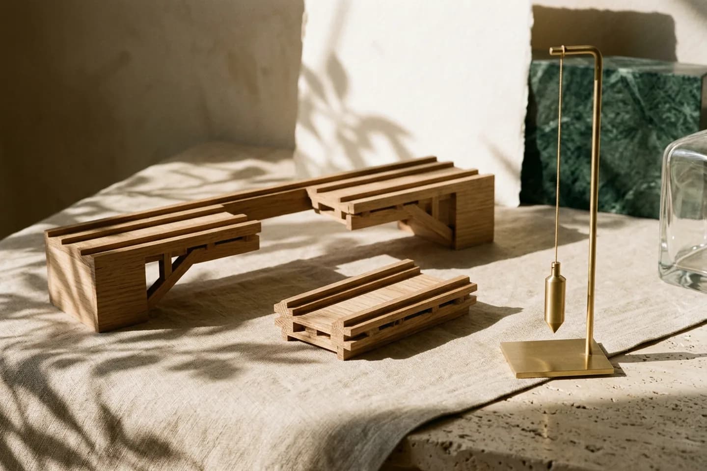 An oak model of a bridge with its middle section lifted off and set beside it, next to a hanging brass plumb line on a linen cloth.